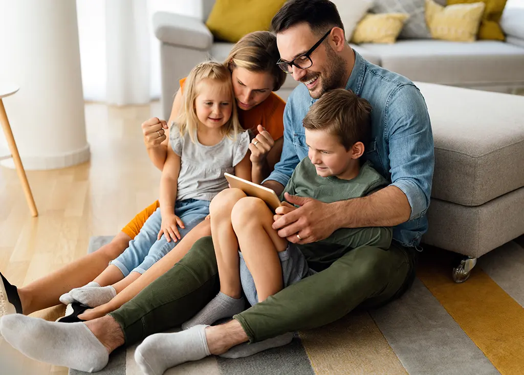 Eltern mit Ihren 2 Kindern und einem Tablet